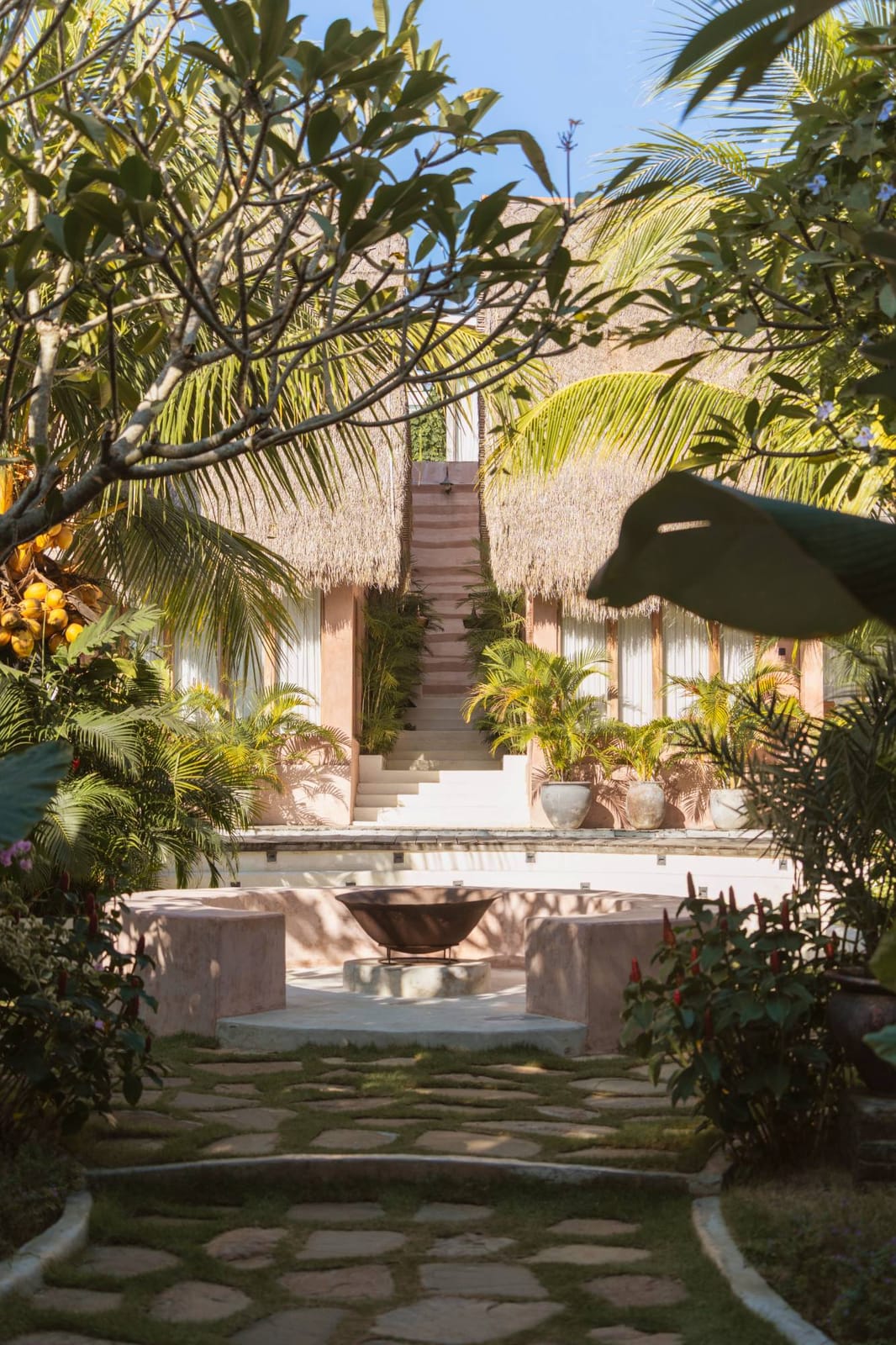 The stone path through the gardens to the fire bowl, with the thatched villas beyond.